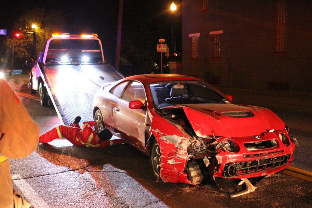 a wrecked car is loaded onto a tow truck after crashing through a brick wall