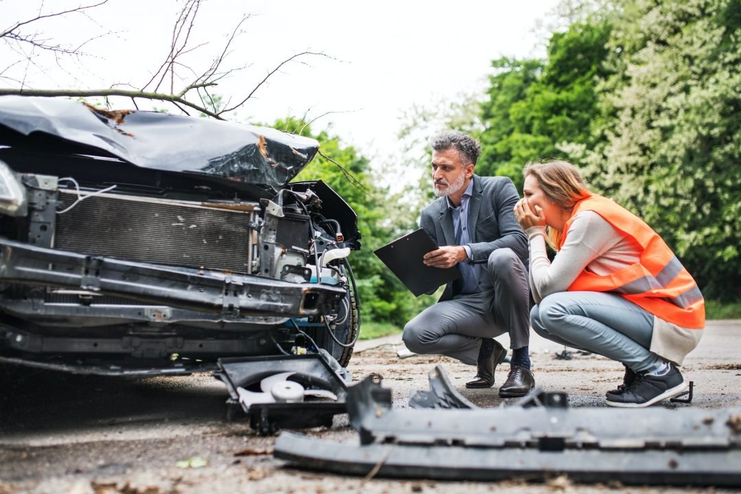 an-insurance-agent-and-a-woman-driver-looking-at-the-car-on-the-road-after-an-accident-.jpg