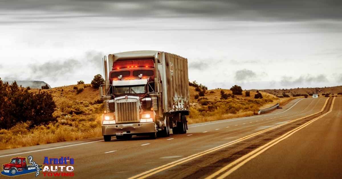 Long-distance tow truck transporting vehicle on I-94 with multiple vehicles in convoy showing interstate highway recovery operation